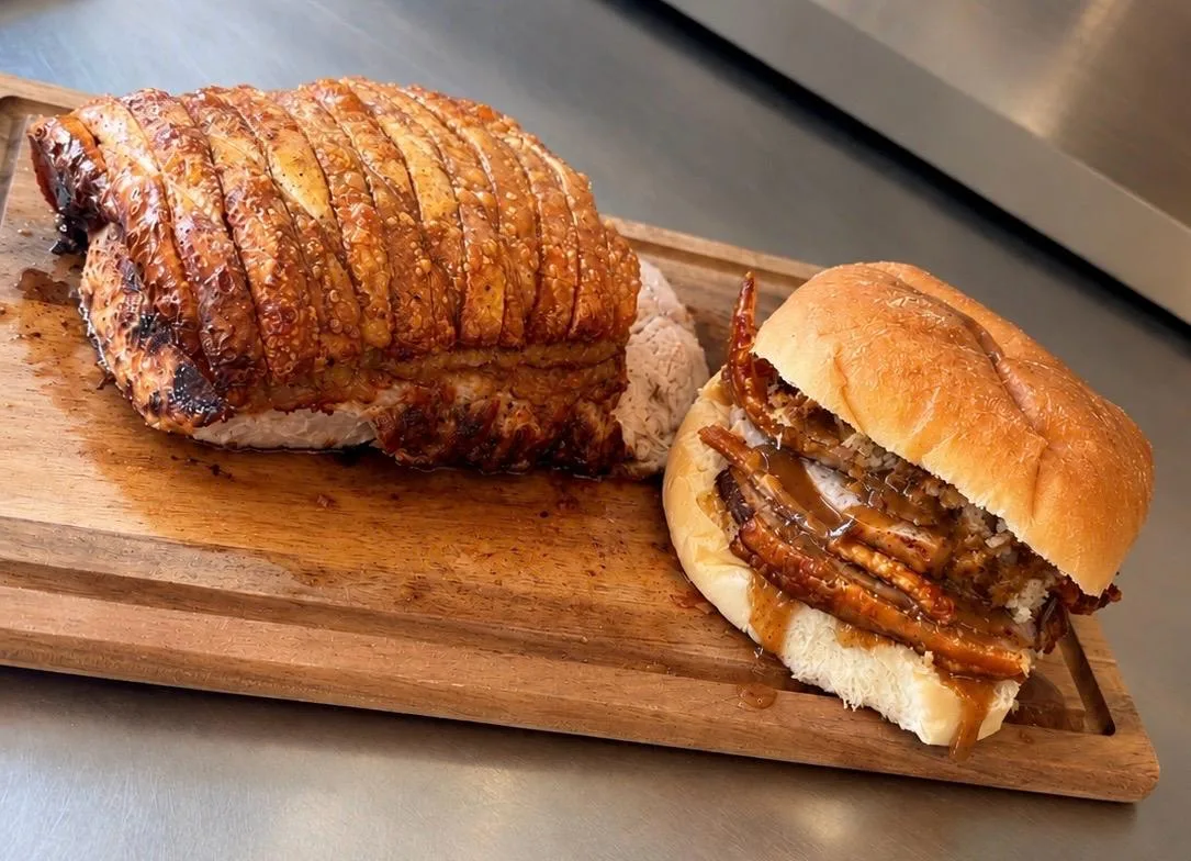 A roast pork roll beside a joint with golden crackling at Slice
